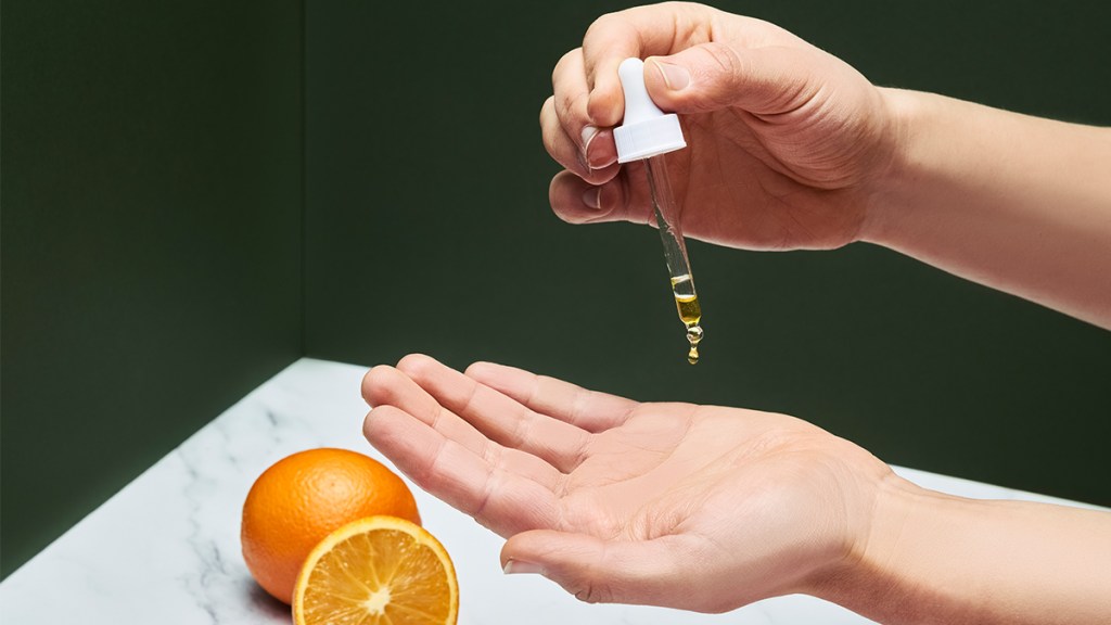 woman applying essential oils to her skin;  Orange essential oil benefits