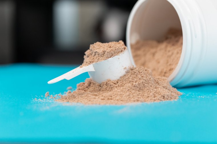 Scoop full of brown or chocolate flavored protein powder.