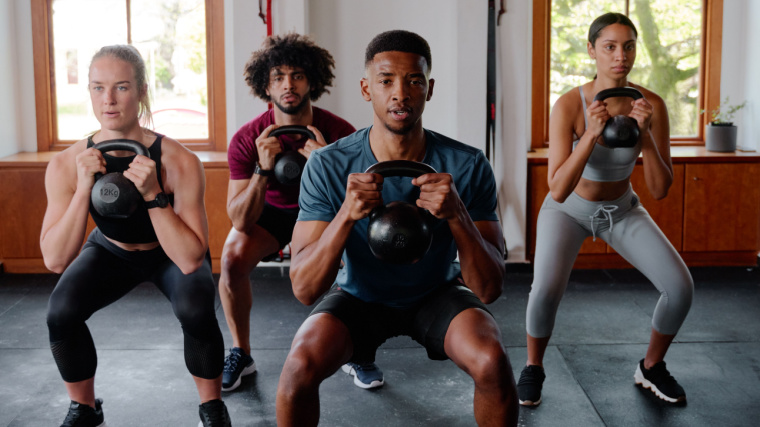 A group of people are doing kettlebell exercises