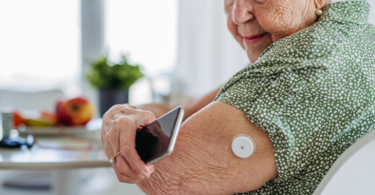 Senior woman using a continuous glucose monitoring device to manage type 2 diabetes. .png